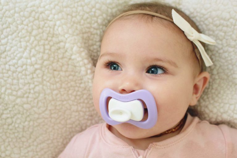 little girl with her green iiamo peace pacifier