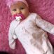 glückliches Baby ganz in pink mit dem passenden pinken Schnuller von iiamo